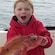 Young boy holding a fish smiles into the camera